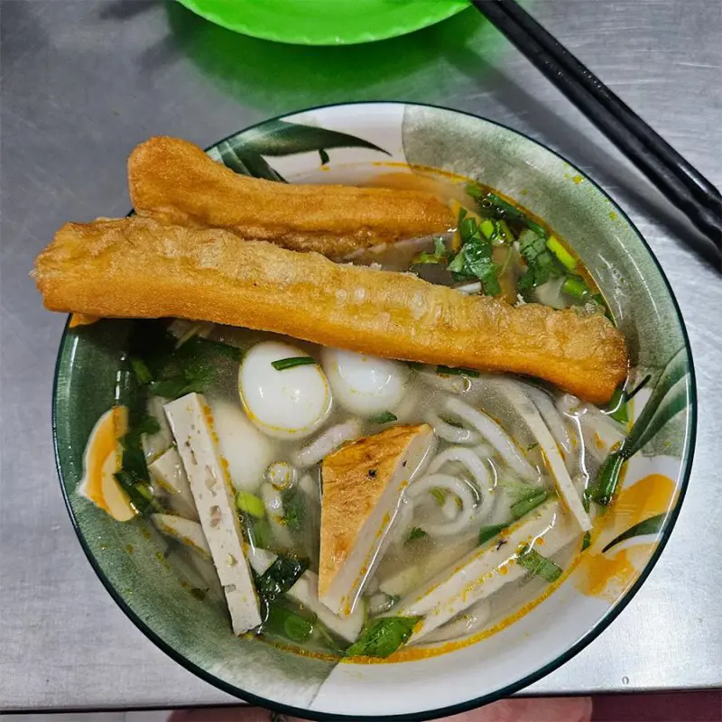 Tô bánh canh Nga Đà Nẵng đầy đặn topping chả, trứng cút và hai chiếc quẩy chiên giòn đặt ngang miệng tô – 3. Bánh canh – tô mì bình dân nhưng rất có võ