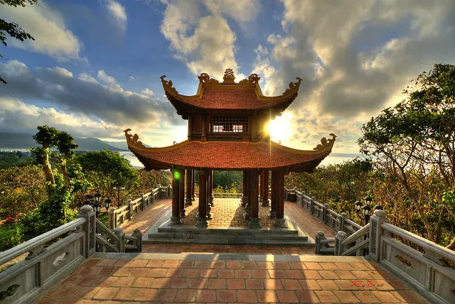 chùa Núi Một ở Côn Đảo, với mái ngói cong, sân gạch và ánh nắng chiếu xuyên qua mây.