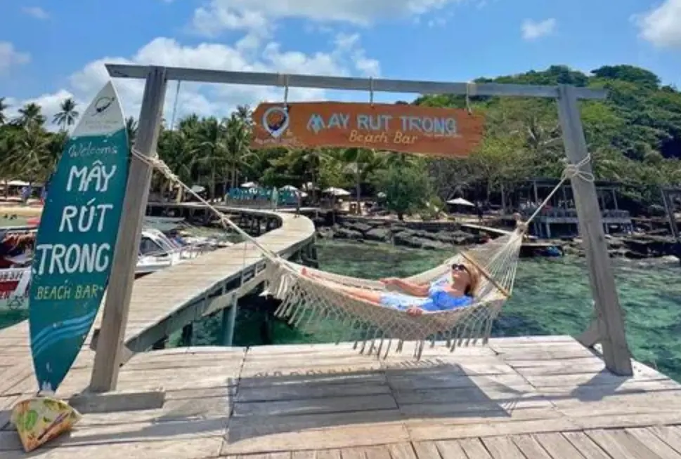 Du khách nằm thư giãn trên chiếc võng khung gỗ tại Mây Rút Trong Beach Bar, Phú Quốc.