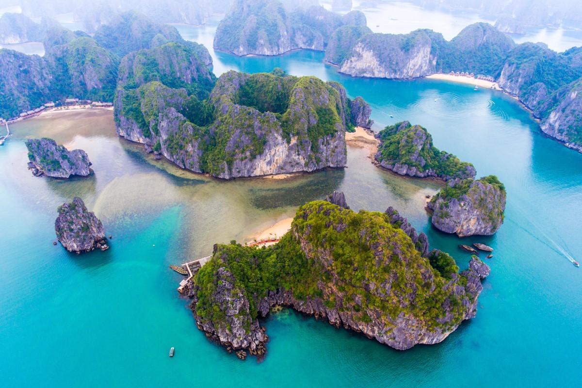 Aerial view of lush green limestone karst islands surrounded by turquoise waters in Lan Ha Bay, Vietnam.